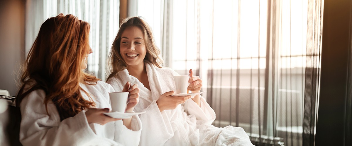 Women relaxing and drinking tea in robes during wellness weekend